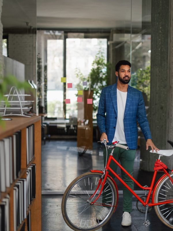 Young multiracial man with bicyckle in an office.